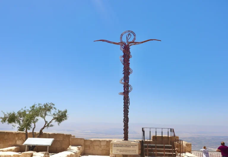 نصب الحية البرونزي على قمة جبل نيبو في مادبا بالأردن، مع منظر وادي الأردن والبحر الميت في الخلفية