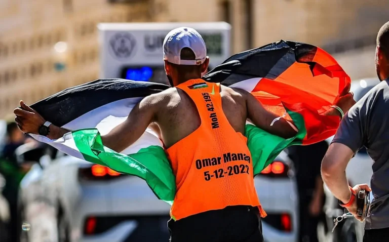 محمد العاصي يركض حاملاً العلم الفلسطيني بعد تحقيقه المركز الثاني في ماراثون فلسطين